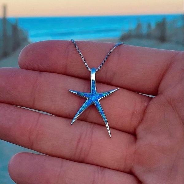 Silver starfish pendant with blue opal inlay on a chain necklace, on hand