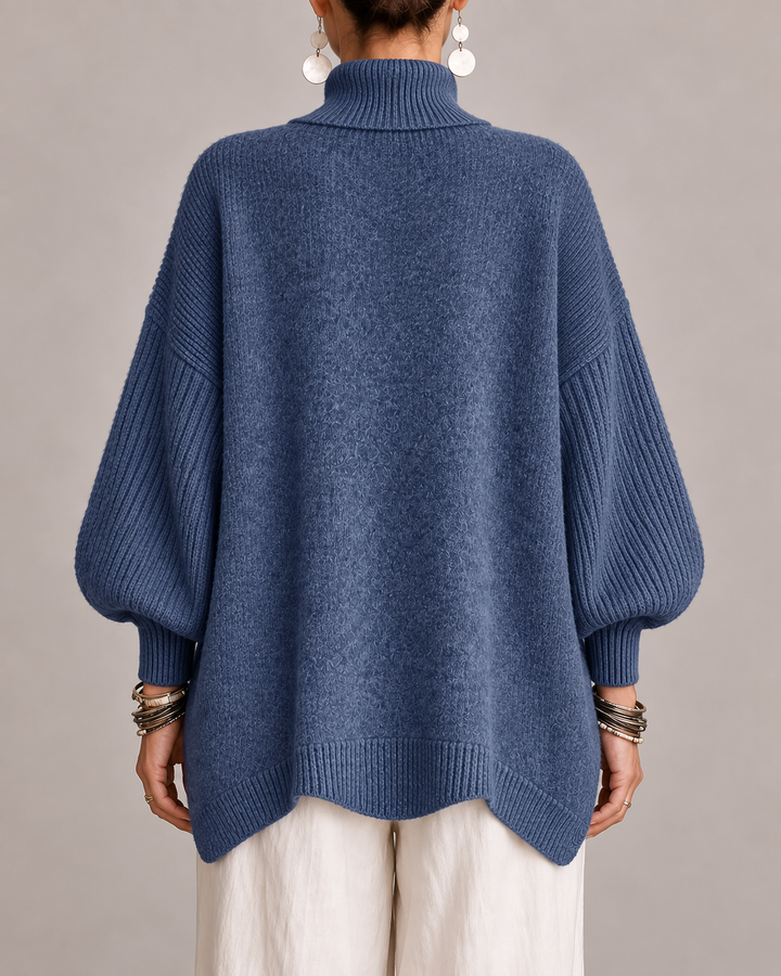 Back view of blue turtleneck knit sweater with ribbed hem and wide sleeves
