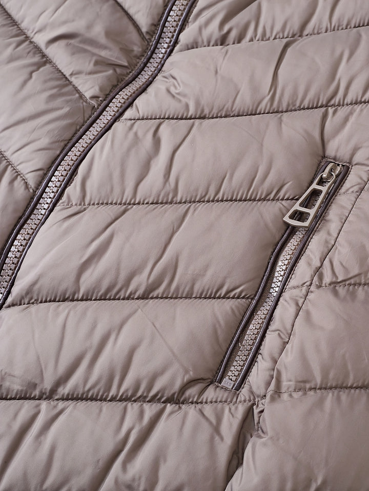 Taupe quilted winter coat fabric detail with visible zipper and seam stitching.