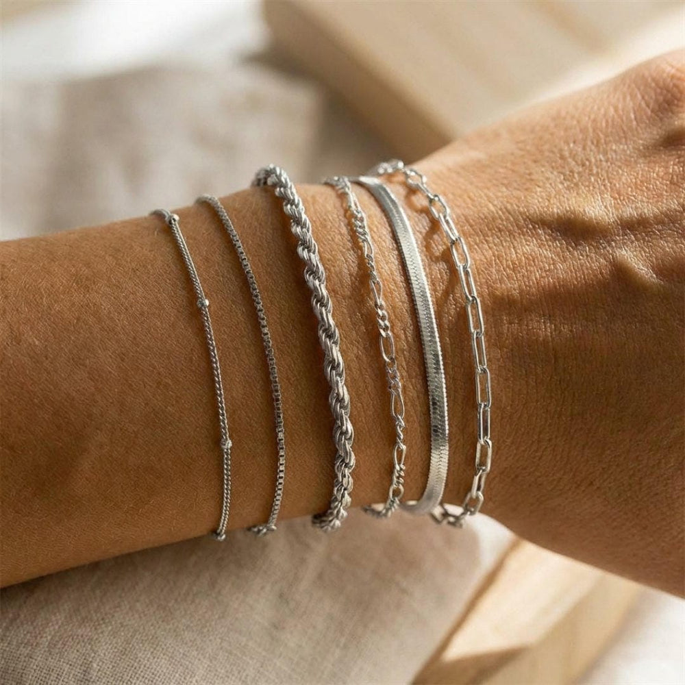 Silver-tone bracelet set with thin chain and curb bracelets stacked on wrist
