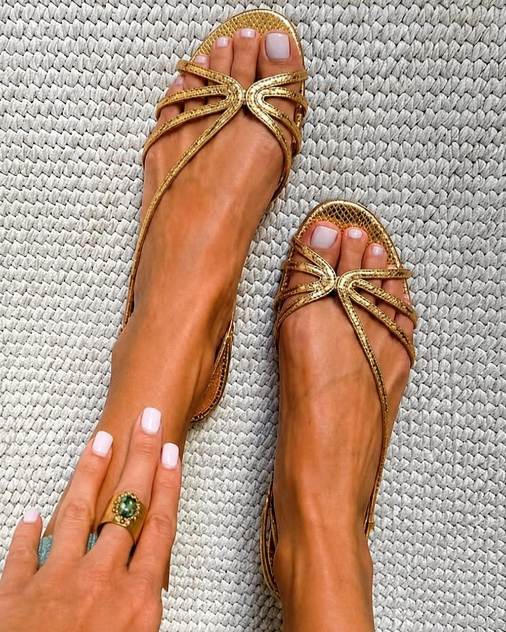 Pair of gold strappy sandals with rhinestone bow detail and flat thong sole