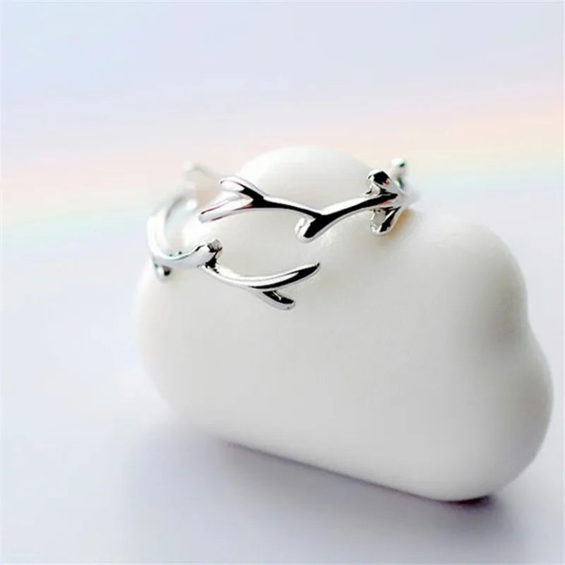 Silver branch-style ring with open oval band and small claw-like leaf details