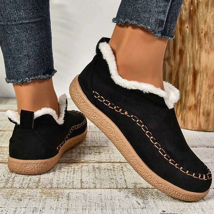 Black ankle boots with sherpa lining, stitched moccasin side seam, and textured sole