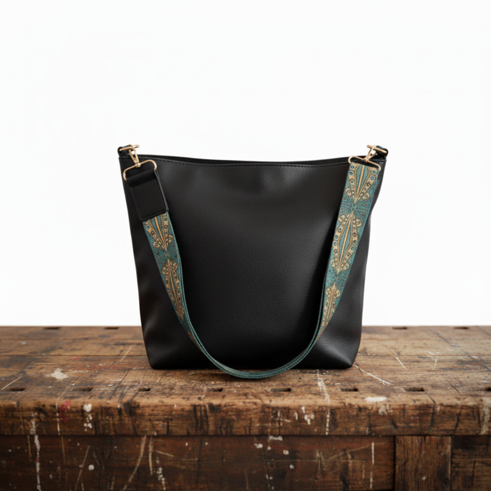 Black vintage leather bag with teal patterned strap and gold-tone hardware