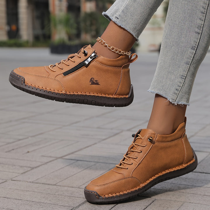 Tan lace-up comfort shoes with side zipper, logo detail, and ankle chain
